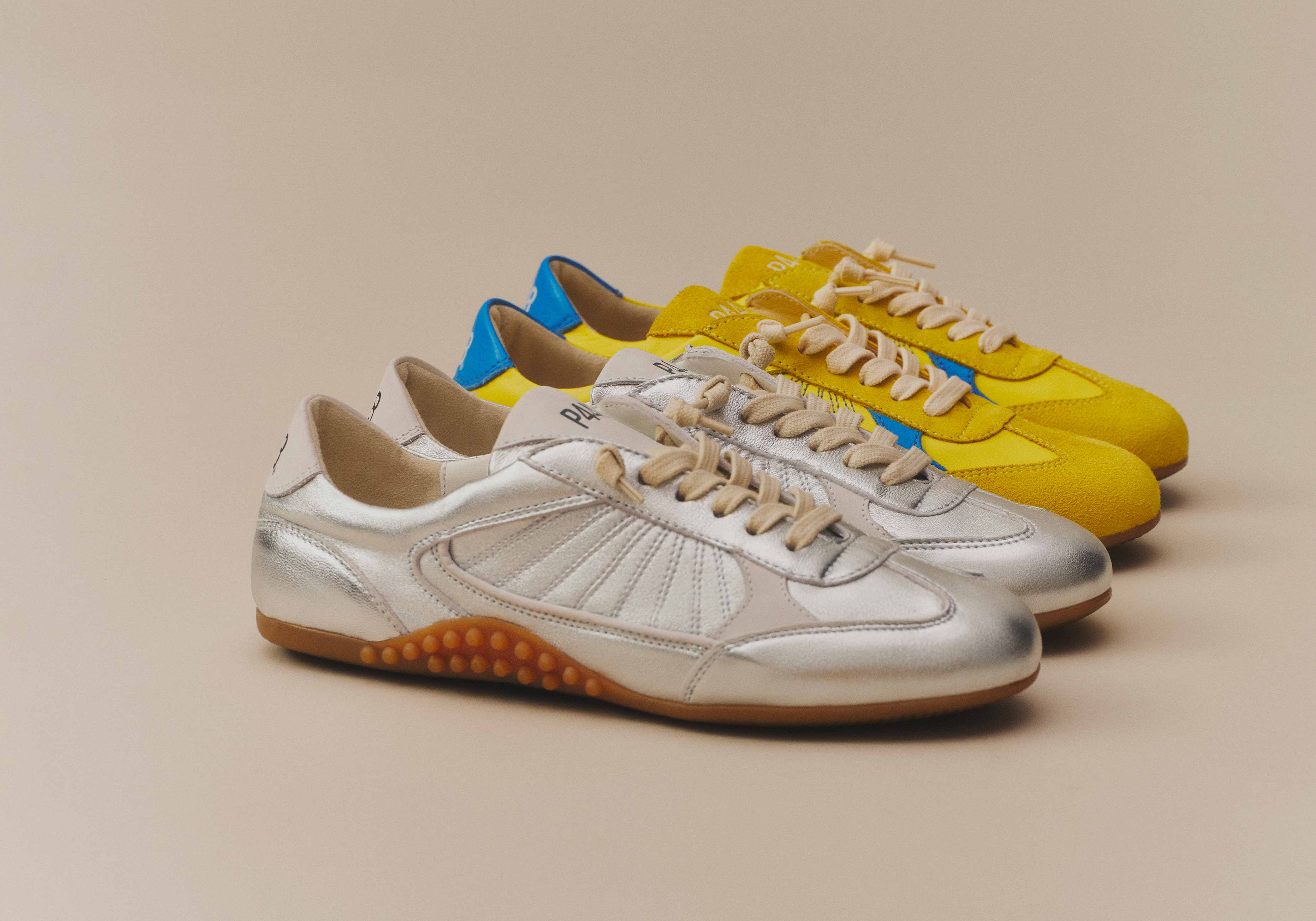 A stylish lineup of P448 sneakers featuring a slim, retro-inspired silhouette. The collection highlights a bold metallic silver finish and vibrant yellow suede with blue accents, accented by cream-colored laces and signature textured rubber soles.