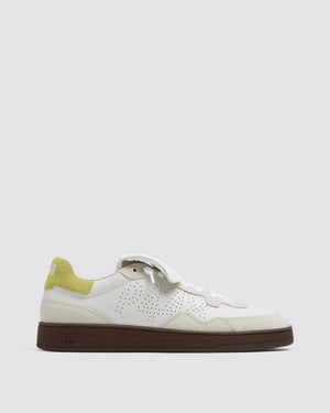 A pair of white low-top sneakers with cream suede trims and a lime green heel tab, featuring white laces and a signature amber gum sole.
